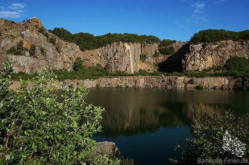 Steile Hammergranitwände am ehemaligen Steinbruch und heutigen Opalsee, Bornholm, Dänemark